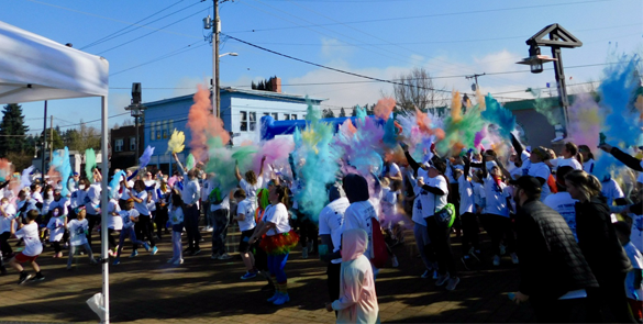 Race participants throw colored chalk into the air at the start of the Color Run